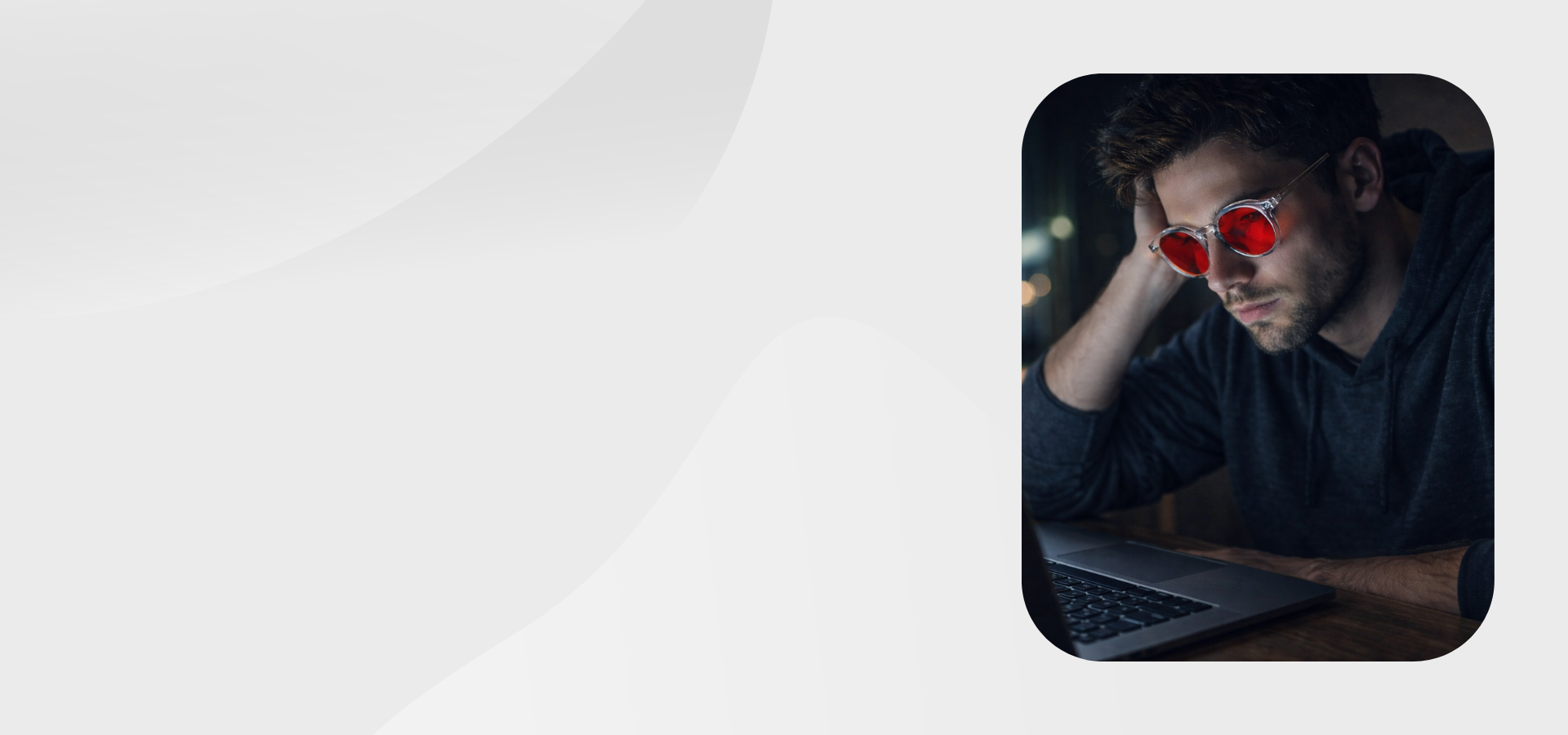 Man wearing sleep glasses working on a laptop with a blurred background